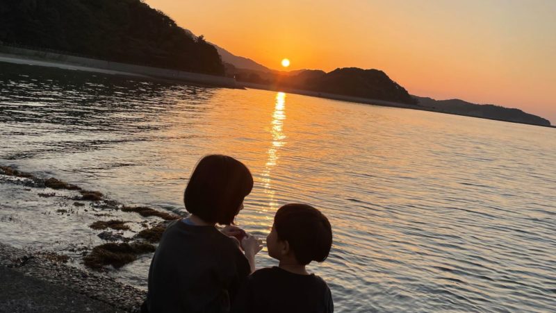 沈む夕日を眺める子どもたち