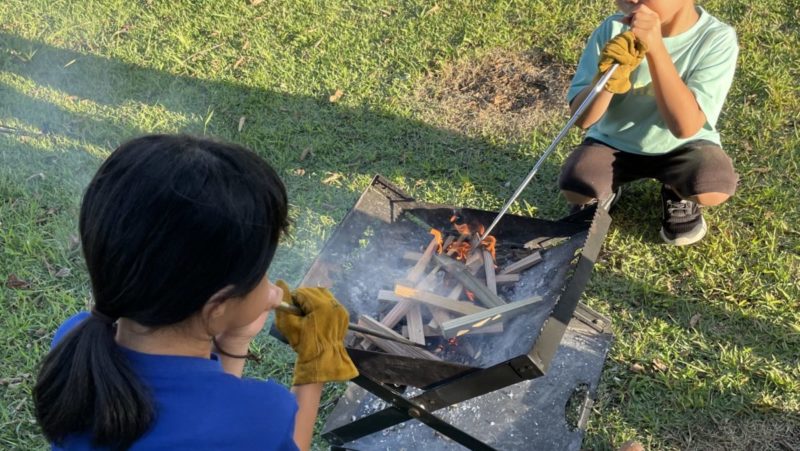 火吹き棒で風を送る子どもたち