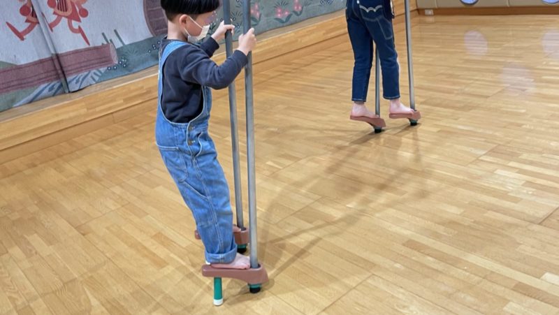 室内遊び場の竹馬に乗る子どもたち